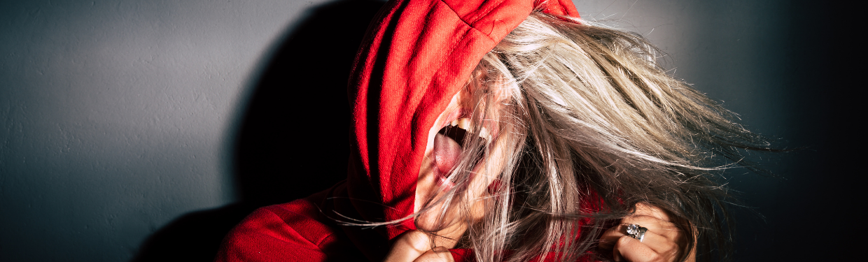 A person screaming in a red hoodie with blonde hair flying around their head