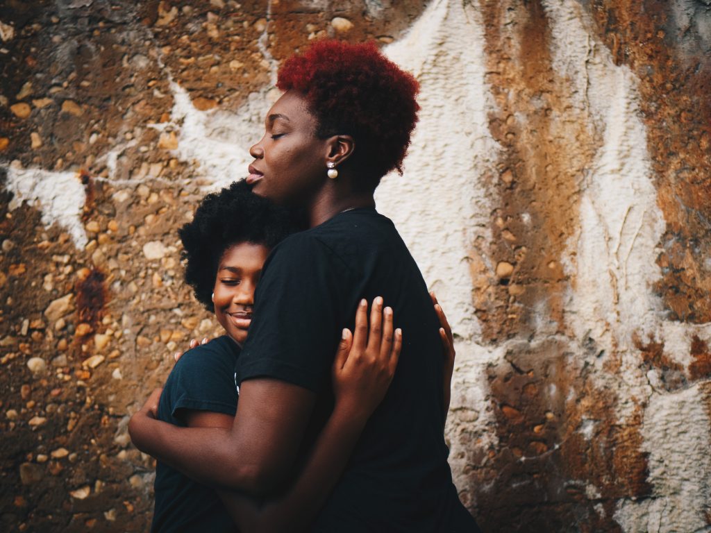 A Black mother hugs her daughter