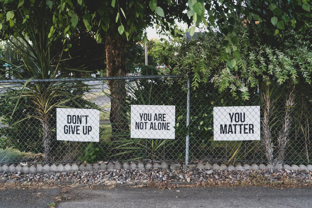 signs behind a fence that read don't give up you are not alone, you matter