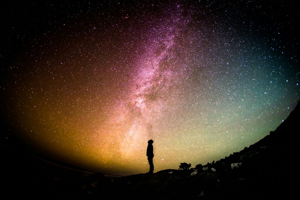 A silhouette of a person against the stars and milky way at night.